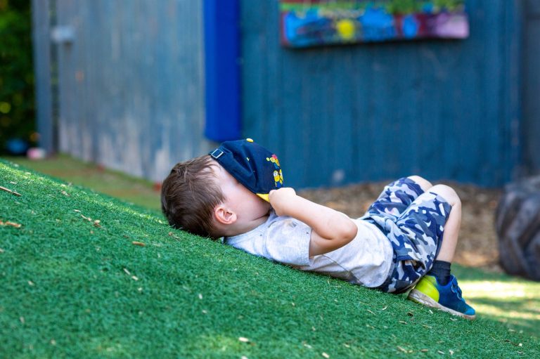 Enfant étendu sur le gazon d'une cour de service de garde