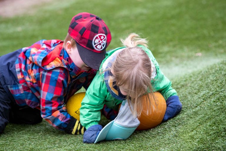 Enfants qui jouent avec des citrouilles dans l'herbe