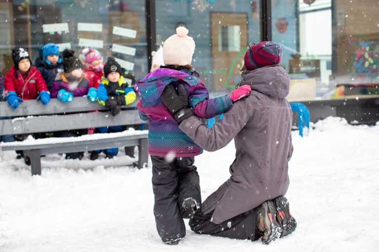 Éducatrice et enfant dans la cour en hiver