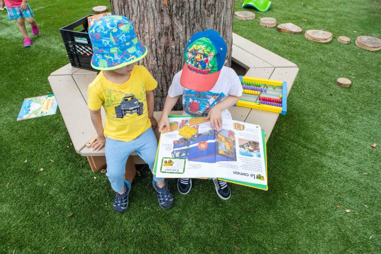 Enfants qui lisent un livre assis dehors